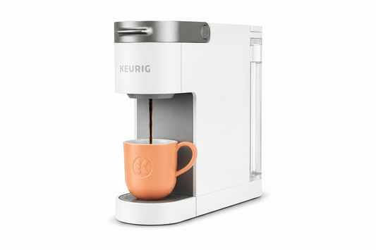 Keurig coffee maker with a peach-colored mug on a white background