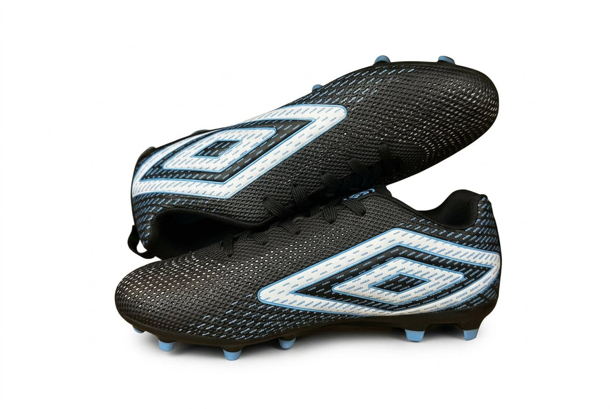 Pair of black and white soccer cleats in a cardboard box on a dark surface