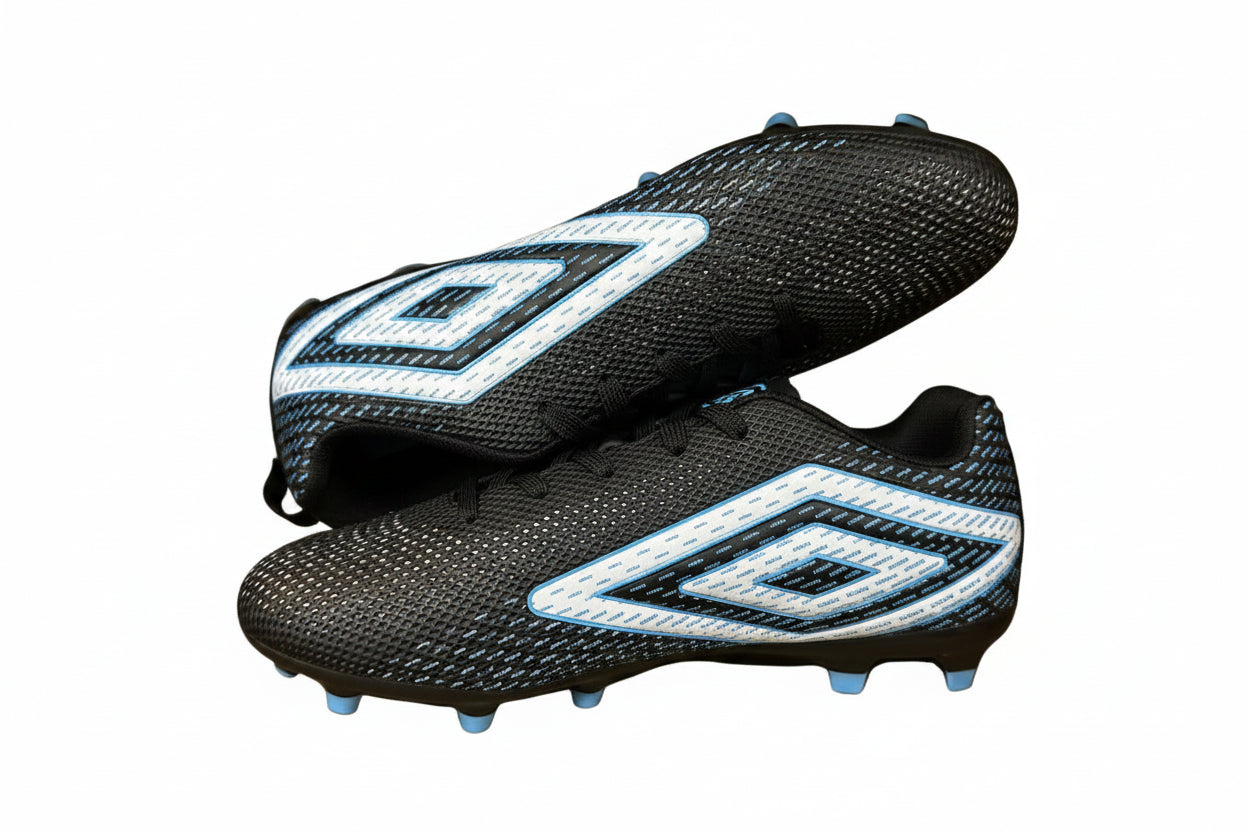 Pair of black and white soccer cleats in a cardboard box on a dark surface